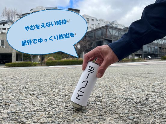 屋外の安全な場所でスプレー缶のガス抜きを行っている画像